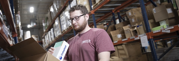 Jake, 180 Medical Shipping Manager, looking at a box of Coloplast catheters in warehouse